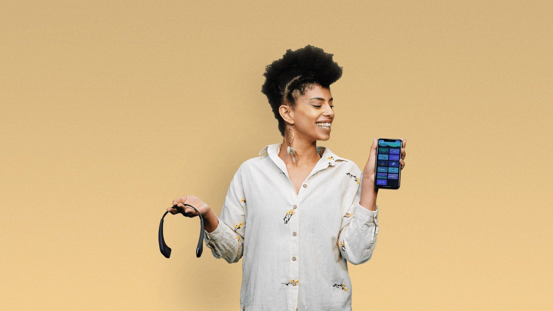 A woman is holding a cell phone and wearing headphones.