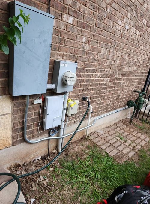 There is a hose attached to the side of a brick building.