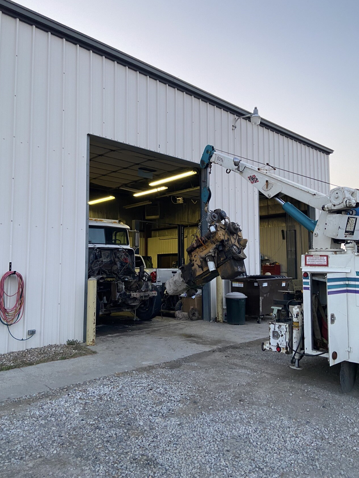 A truck with a crane attached to it is parked in front of a garage.
