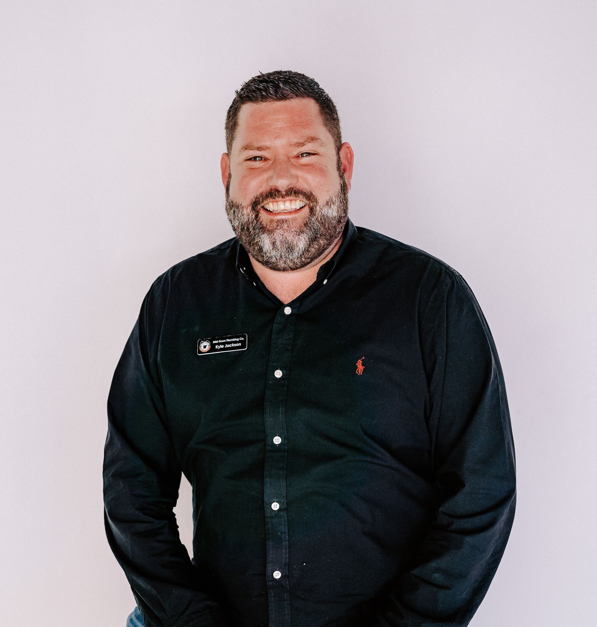 A man with a beard is wearing a black shirt and smiling