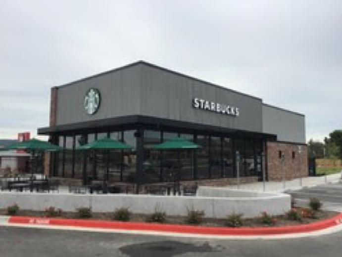 A starbucks restaurant with green umbrellas in front of it