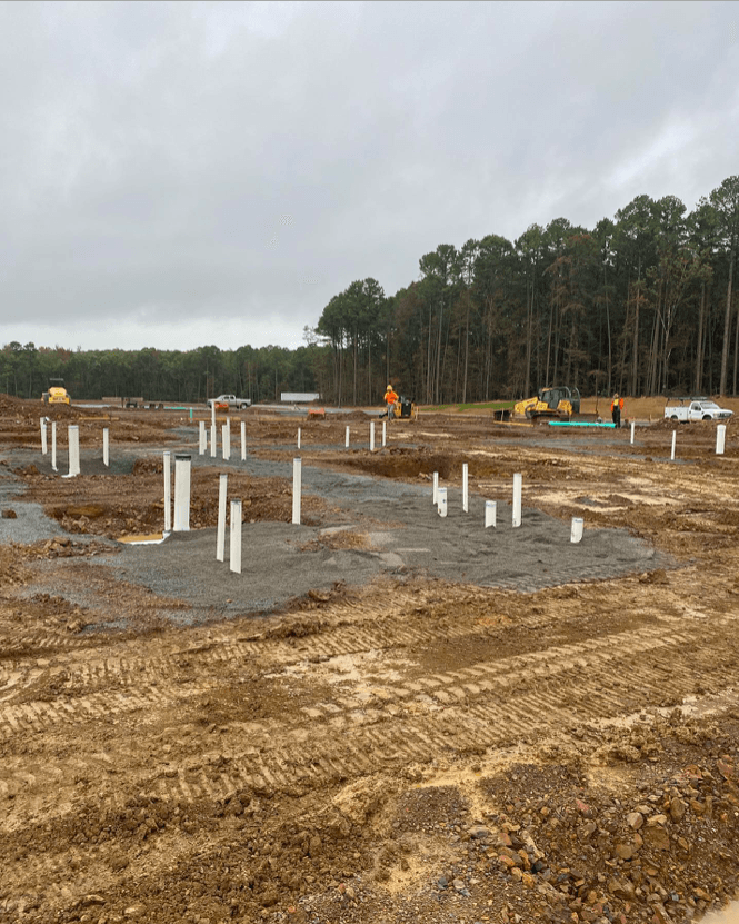 A construction site with a lot of pipes and trees in the background