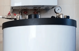 A close up of a water heater with a gauge on top of it.