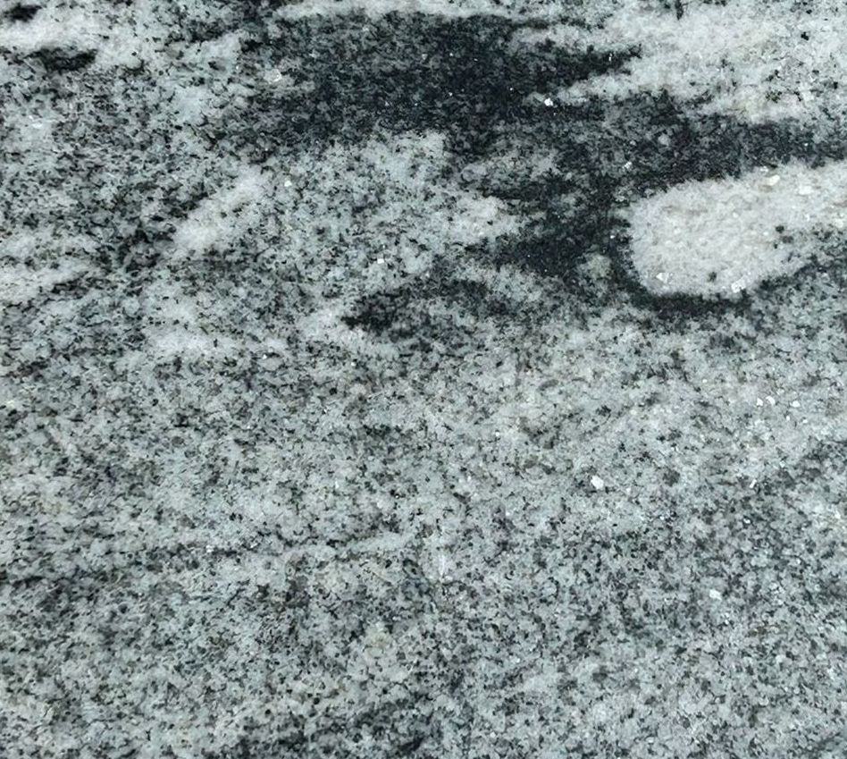 A square piece of granite is sitting on a concrete surface.