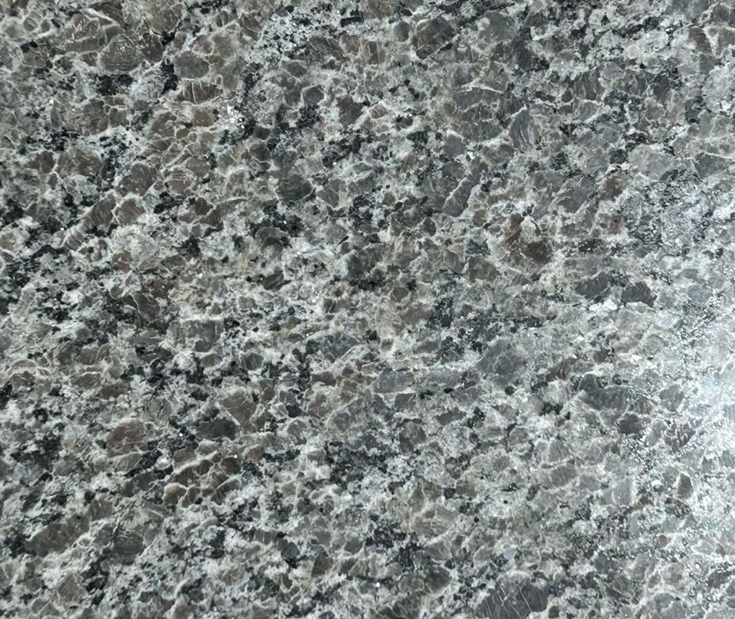 A square piece of granite is sitting on a concrete surface.