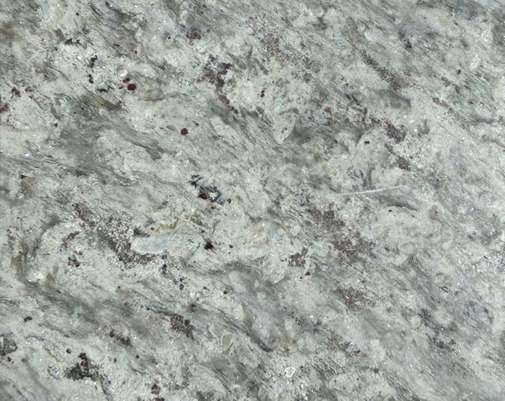 A square tile with a sticker on it is sitting on a concrete surface.