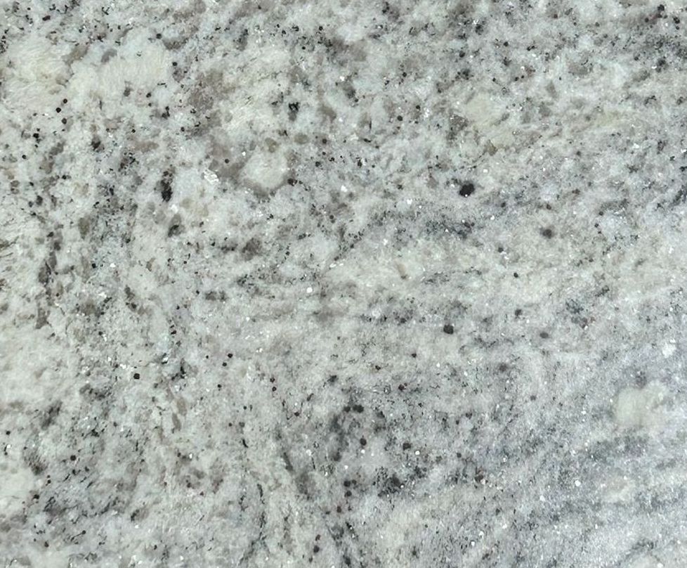 A square piece of granite is sitting on a concrete surface.