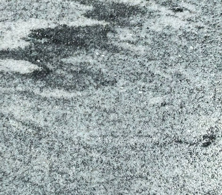 A square piece of granite is sitting on top of a concrete surface.