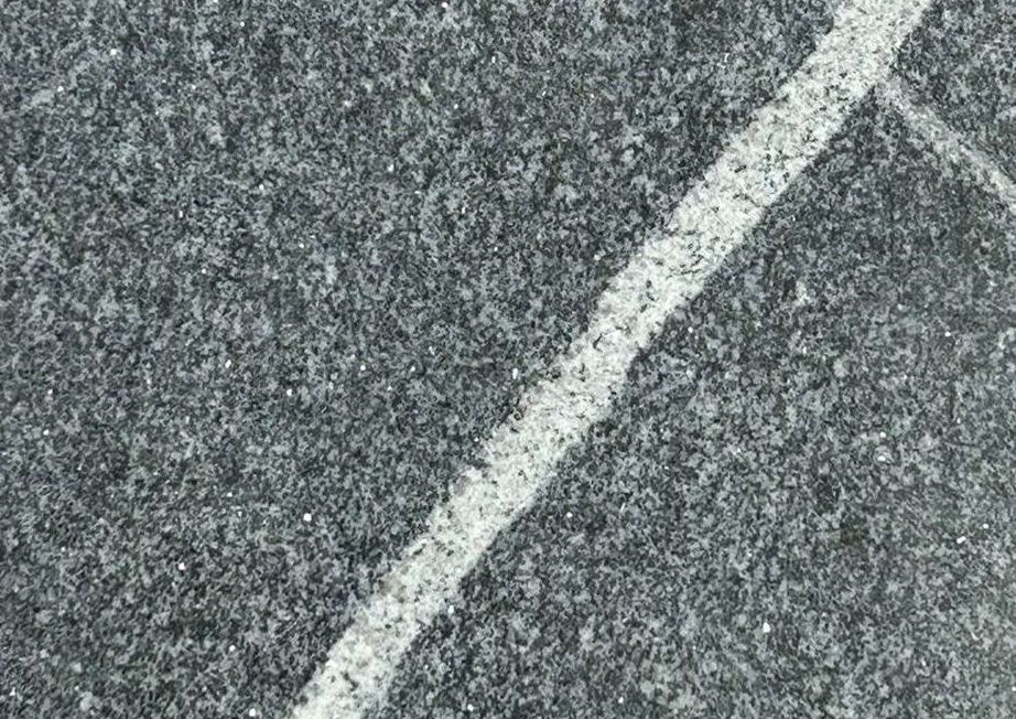 A black and white tile with a white line on it is sitting on a concrete surface.