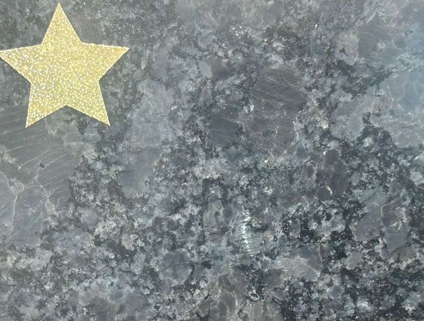 A black tile with a yellow star on it is sitting on a concrete surface.