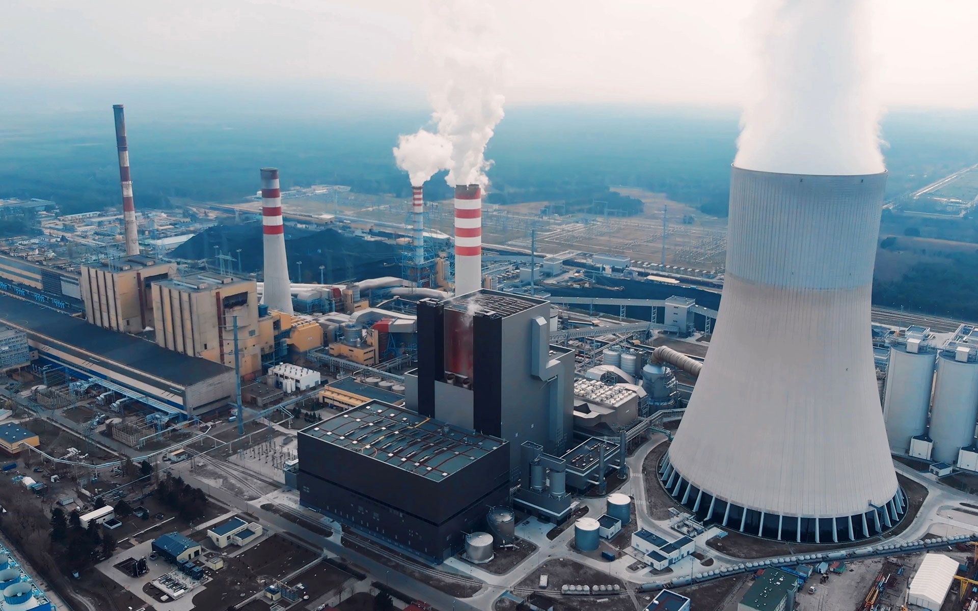 An aerial view of a nuclear power plant with smoke coming out of the chimneys.
