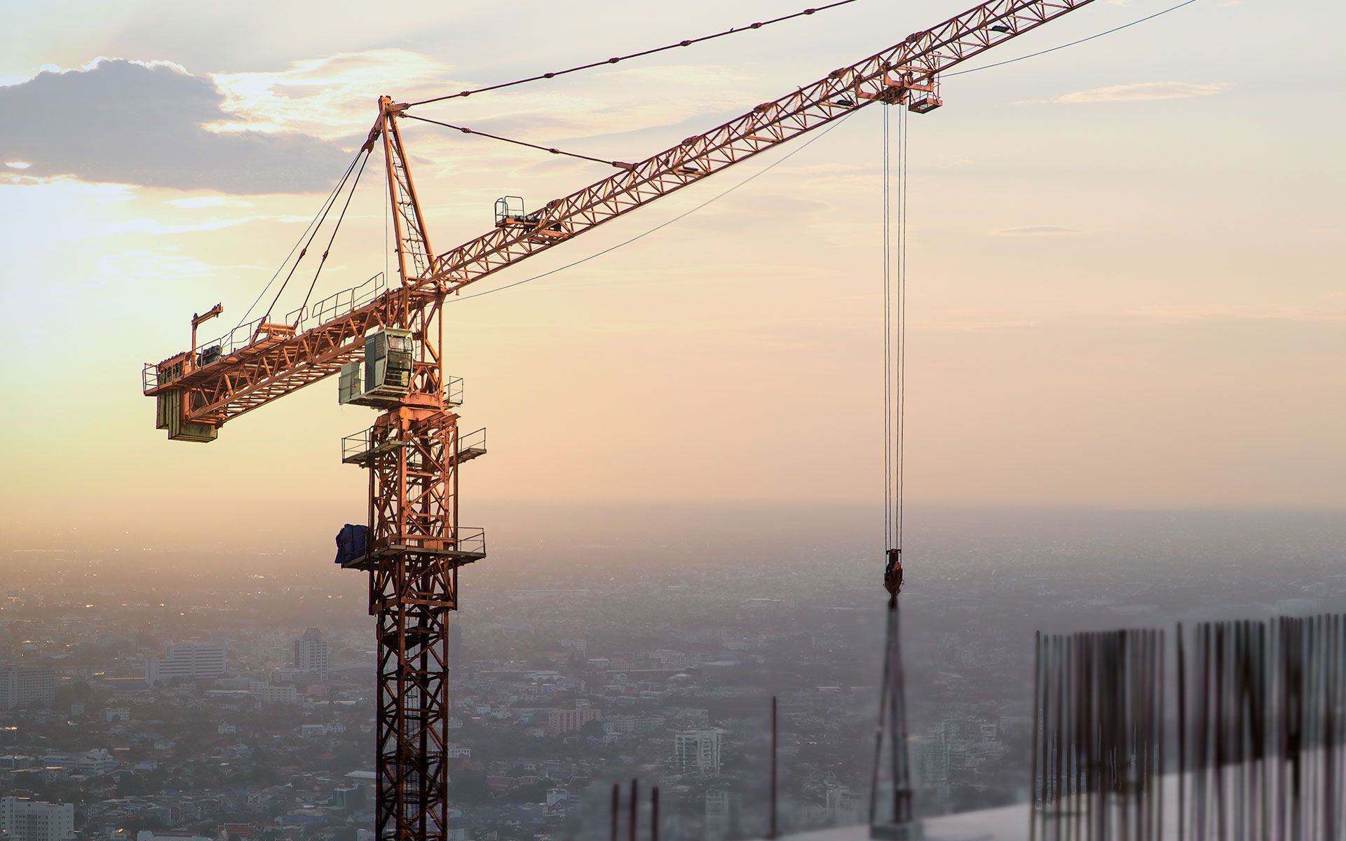 A construction crane is sitting on top of a building under construction.