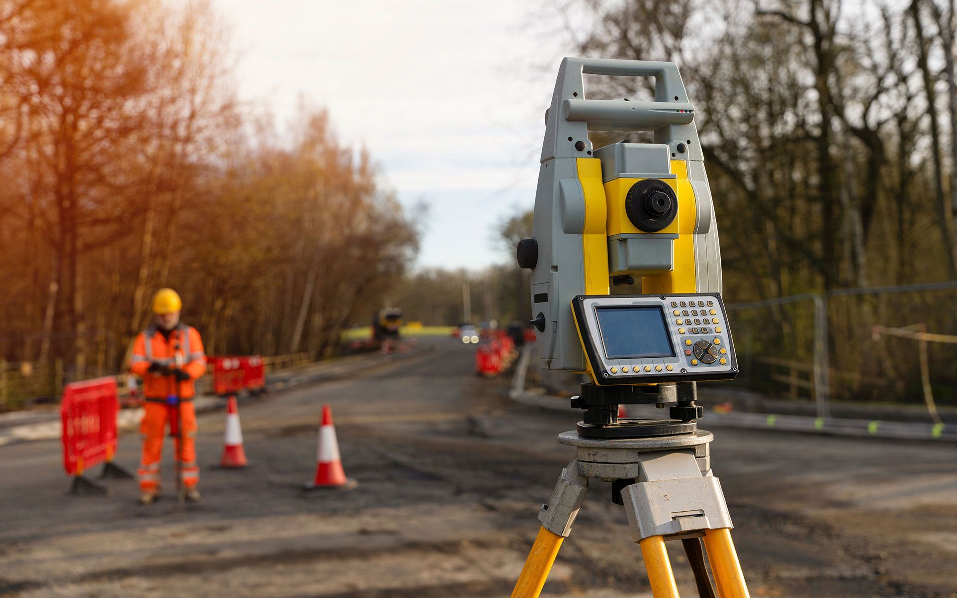 A man is standing next to a total station on a construction site.