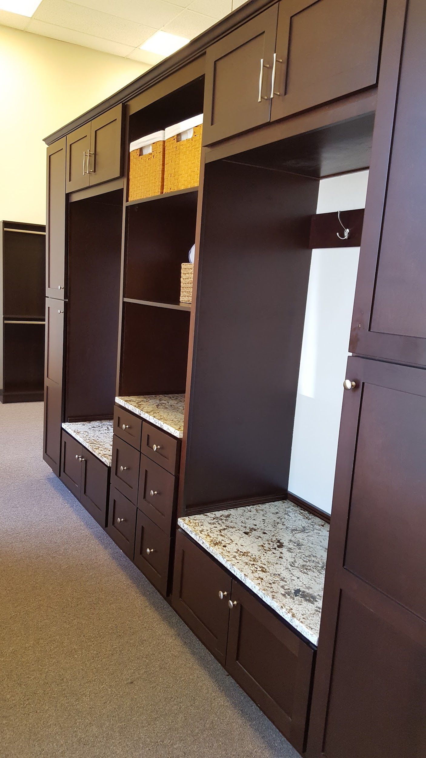 Dark brown built-in storage unit with bench seating and cubbies; beige carpet.