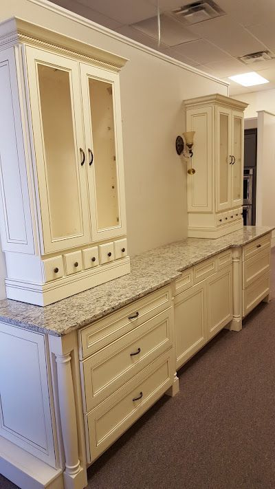 Cream-colored kitchen cabinets with granite countertop against a white wall; tall glass-door cabinet.