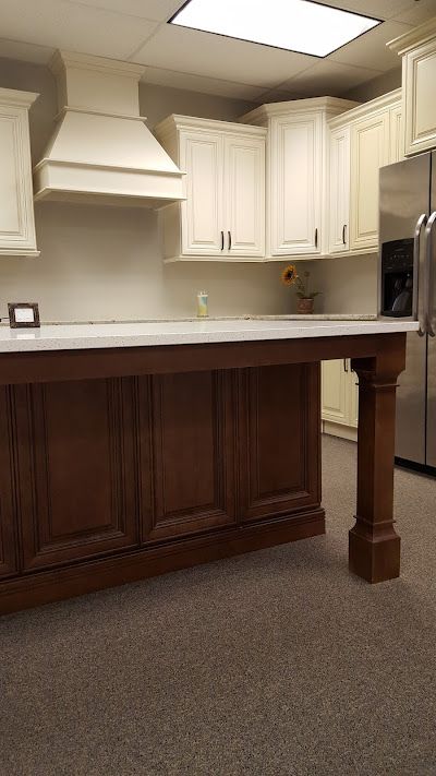 Kitchen with white cabinets, brown island, stainless steel appliances, and carpeted floor.