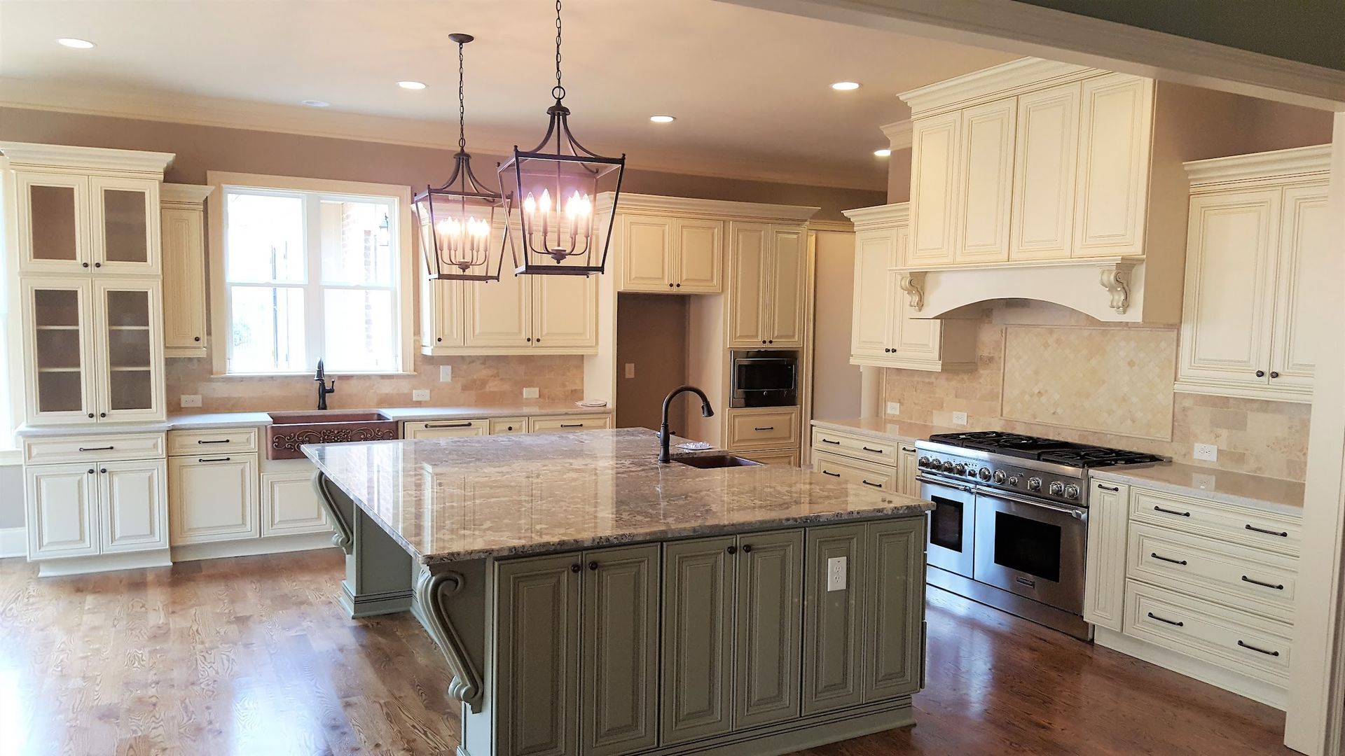 Spacious kitchen with cream cabinets, green island, granite countertops, and hardwood floors.