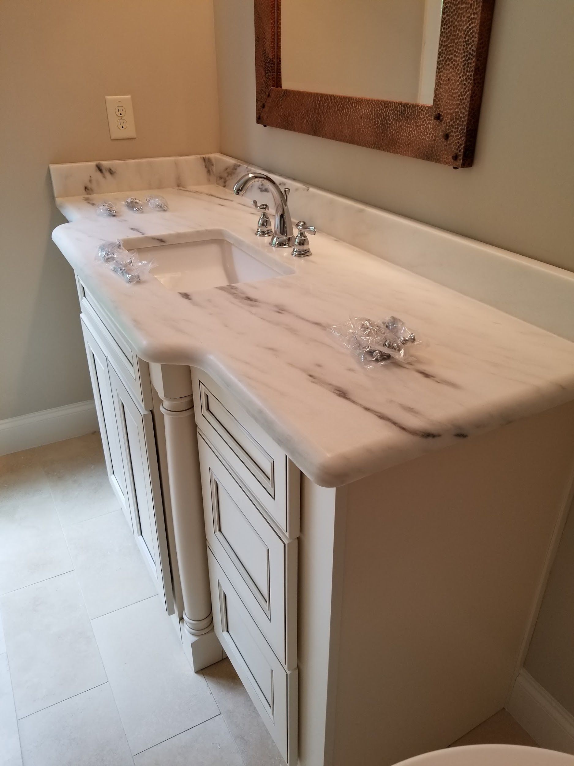 White marble bathroom vanity with double sinks, silver fixtures, and decorative knobs.