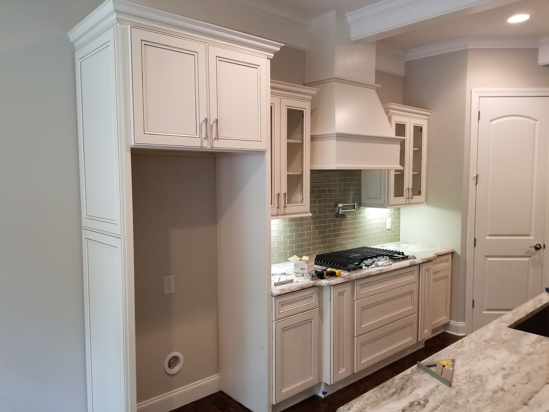 White kitchen cabinets with a built-in refrigerator space, range hood, and stove.