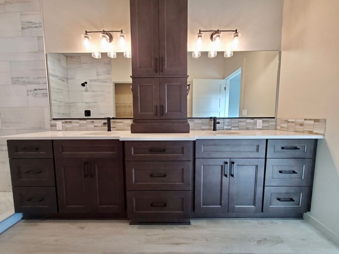 Dark wood double vanity with white countertop, two mirrors, and a tall cabinet in a bathroom.