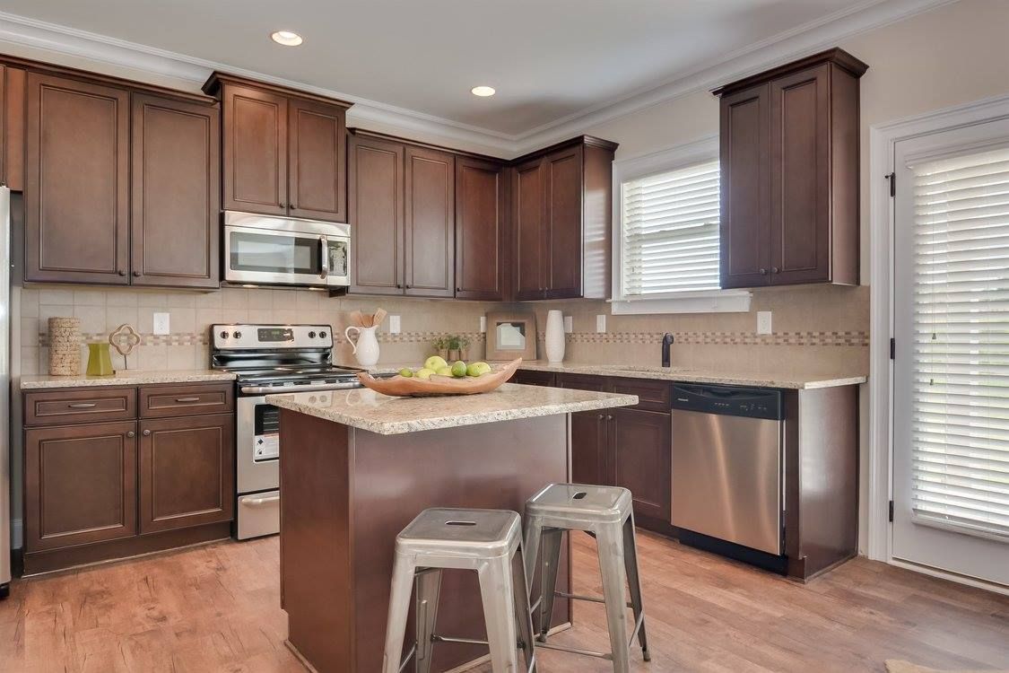 Kitchen with brown cabinets, stainless steel appliances, and a granite countertop island.