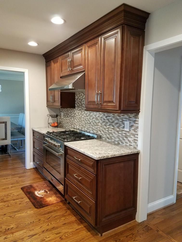 Kitchen with brown cabinets, stainless steel appliances, granite countertops, and mosaic backsplash.