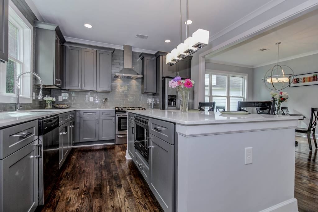 Gray kitchen with island, stainless steel appliances, and dark wood floors.