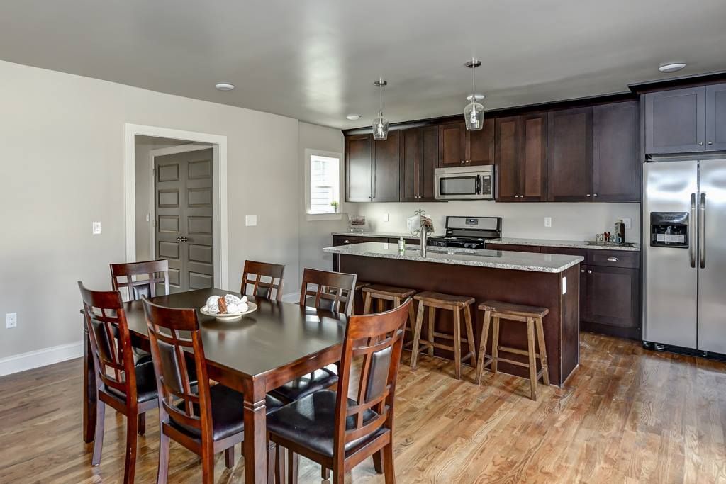 Spacious kitchen and dining room with dark cabinets, island, dining table, and stainless steel appliances.