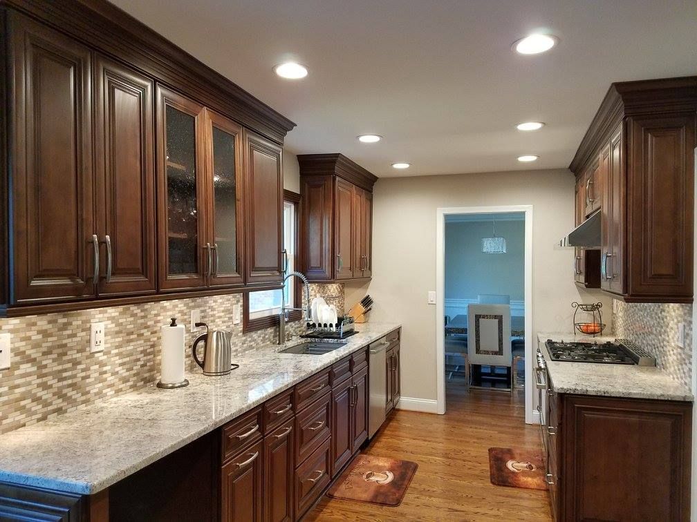 Dark wood kitchen with granite countertops, mosaic backsplash, and stainless steel appliances.