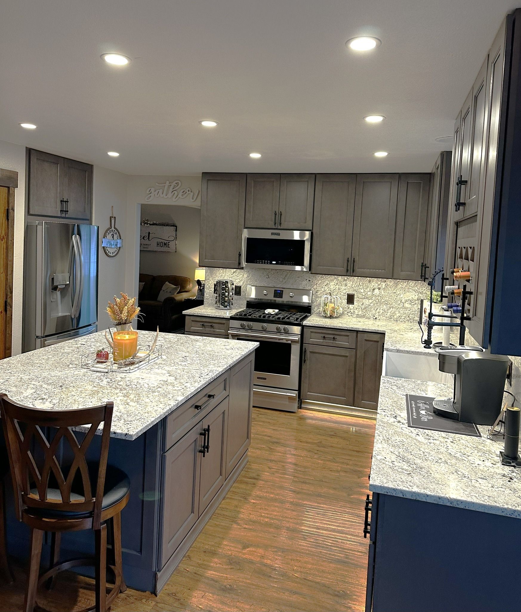 Kitchen with island, cabinets, and appliances.  Gray and blue cabinets, granite countertops, wood flooring.