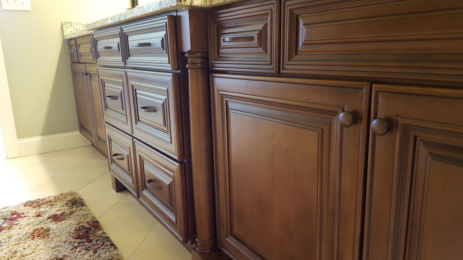 Brown wooden bathroom cabinets with decorative trim, drawers, and knobs.