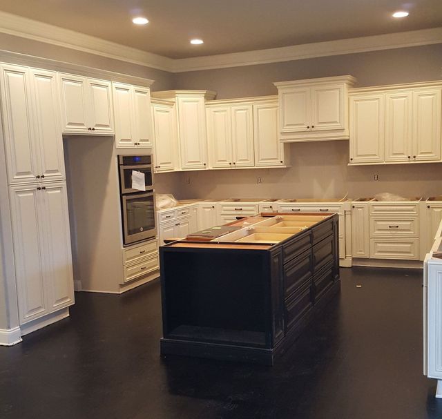 Kitchen with white cabinets, black island, and dark flooring.
