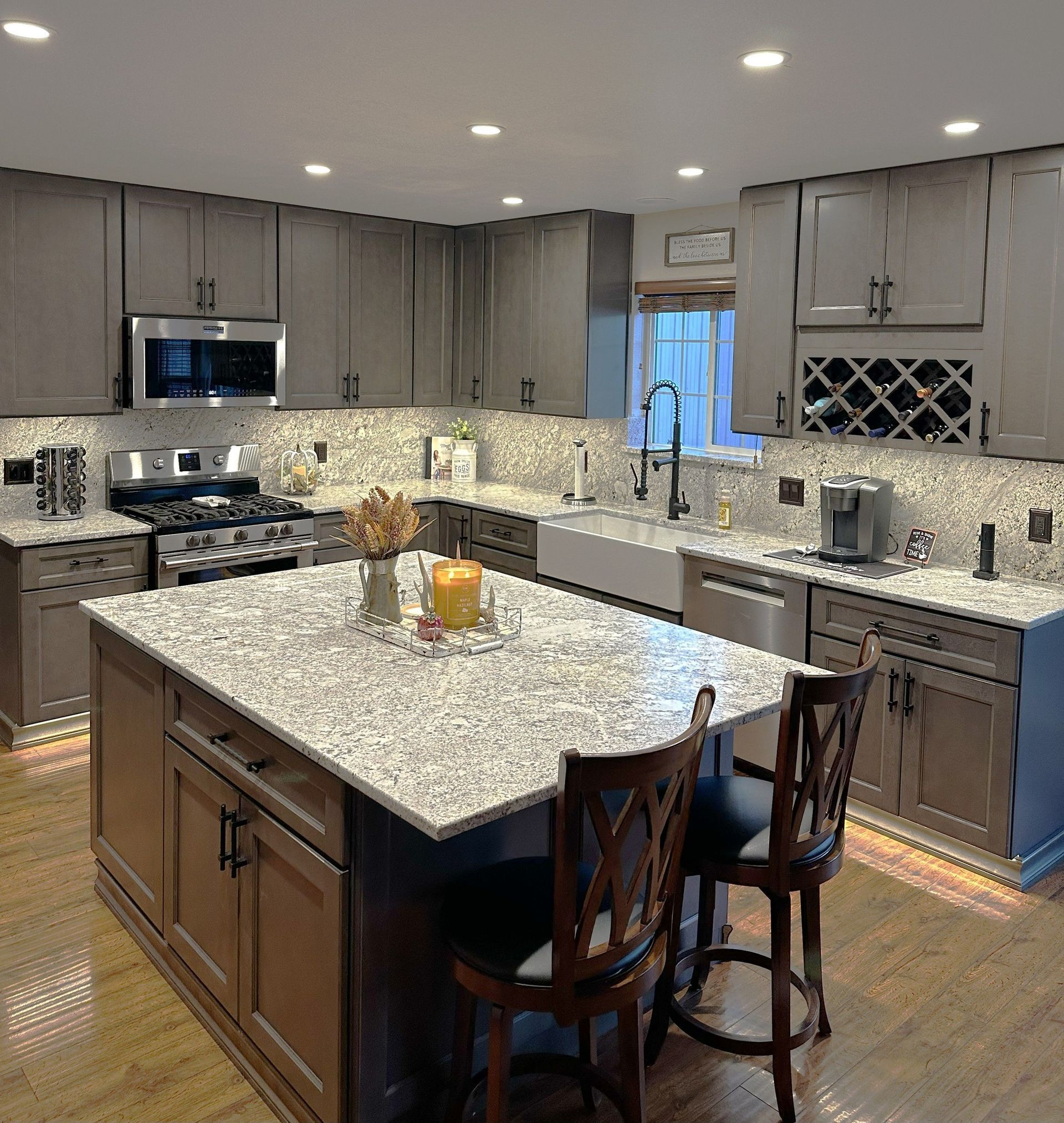 Kitchen with gray cabinets, granite countertops, and a large island with seating.