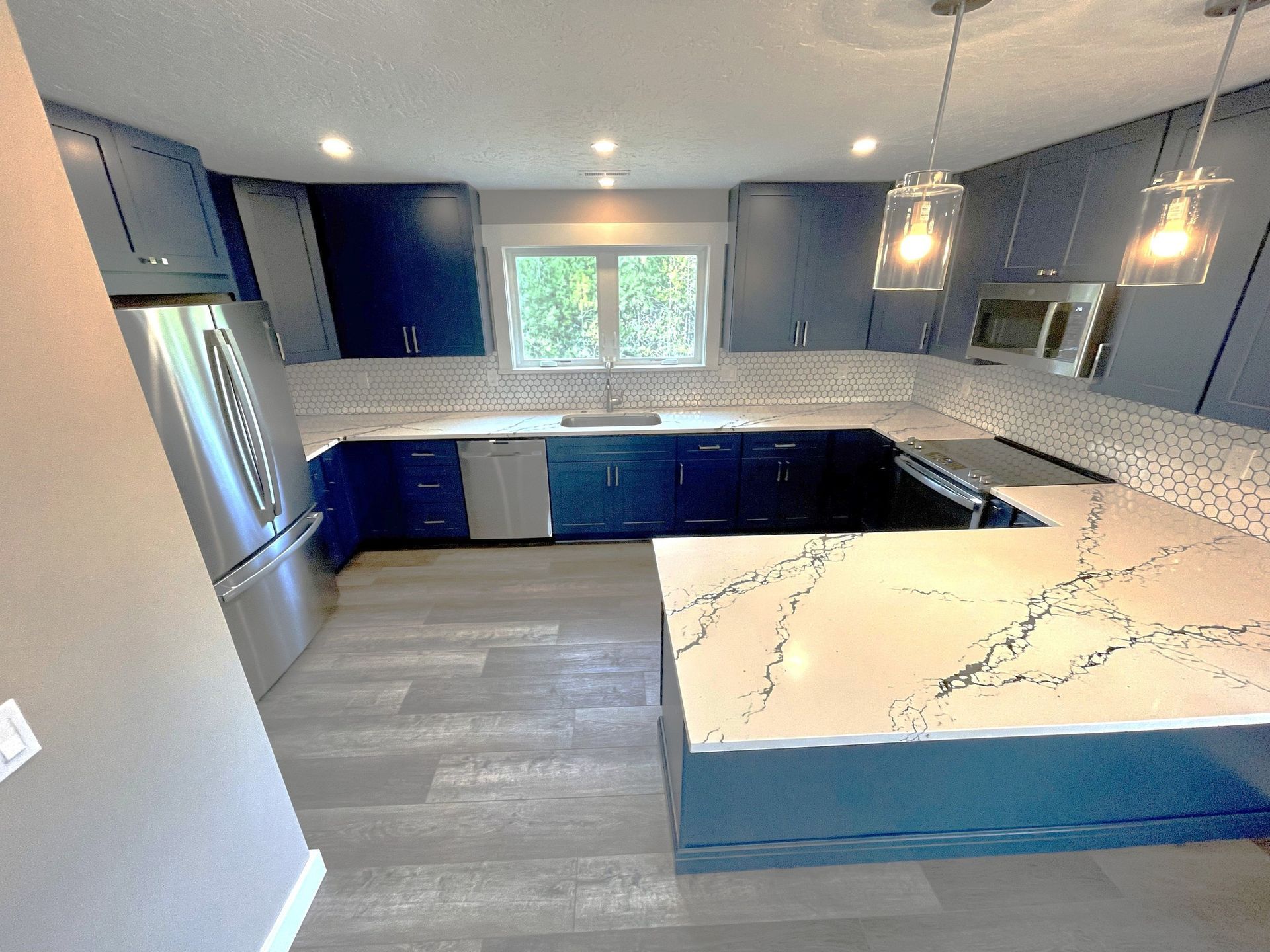 Modern kitchen with blue cabinets, white countertop, and stainless steel appliances.