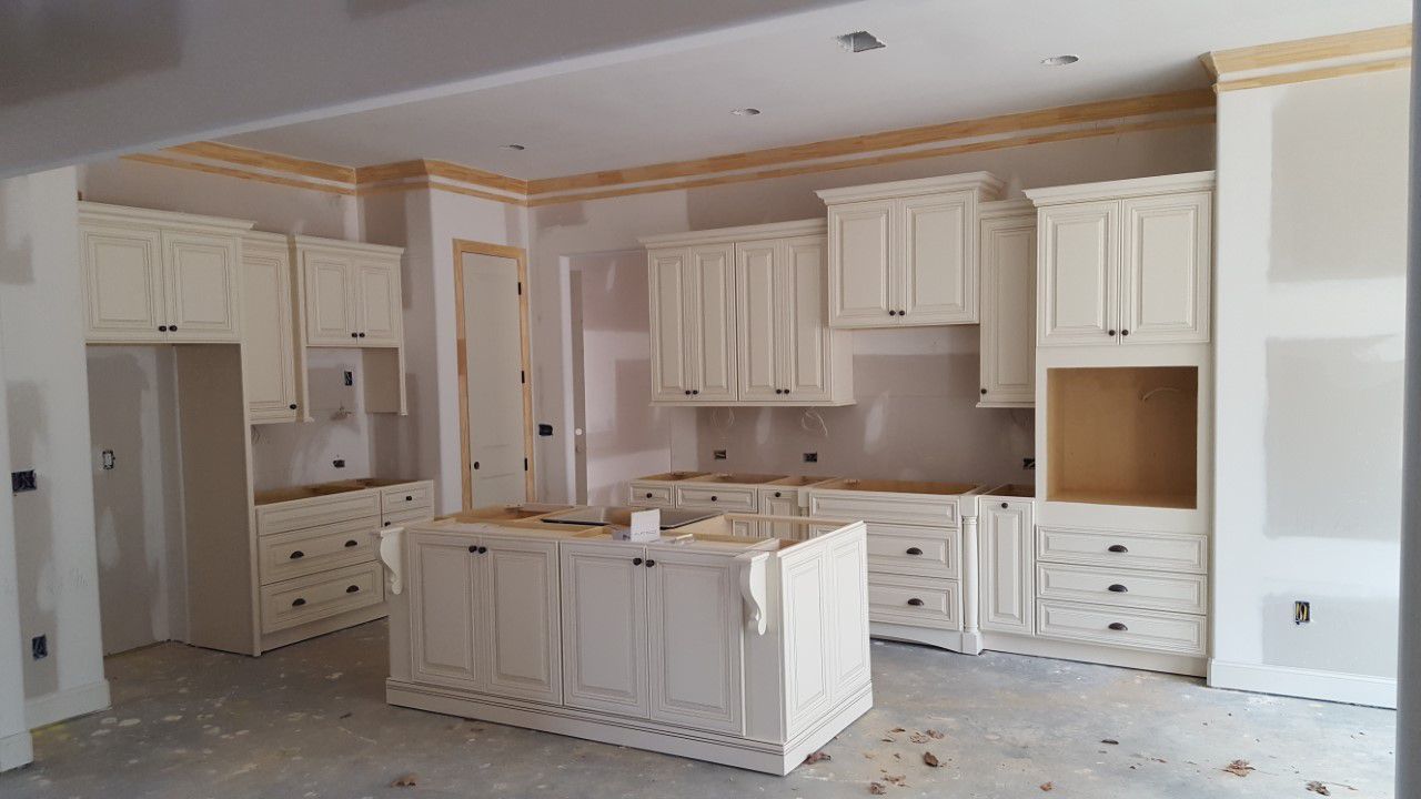 Unfinished kitchen with cream cabinets and island. Drywall, construction setting.