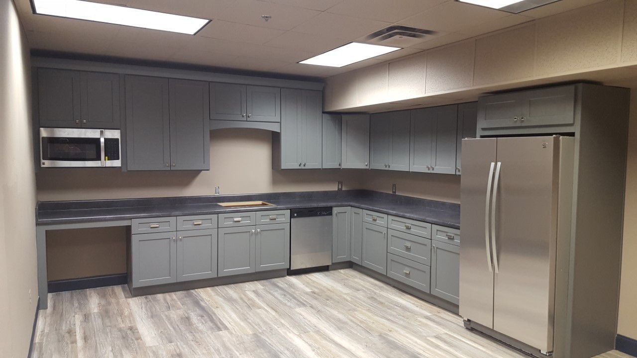 Grey office kitchen with stainless steel appliances and accessible countertop.