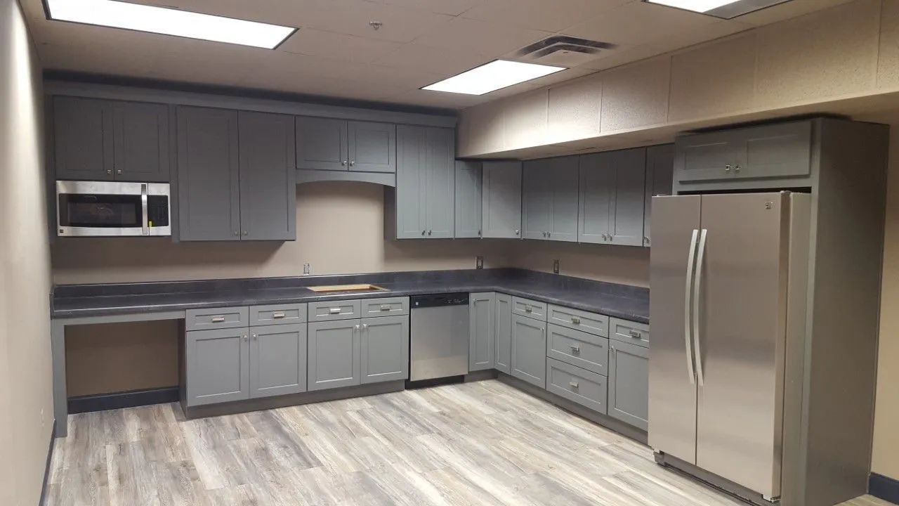 A gray kitchen with cabinets, stainless steel appliances, and wooden floor.