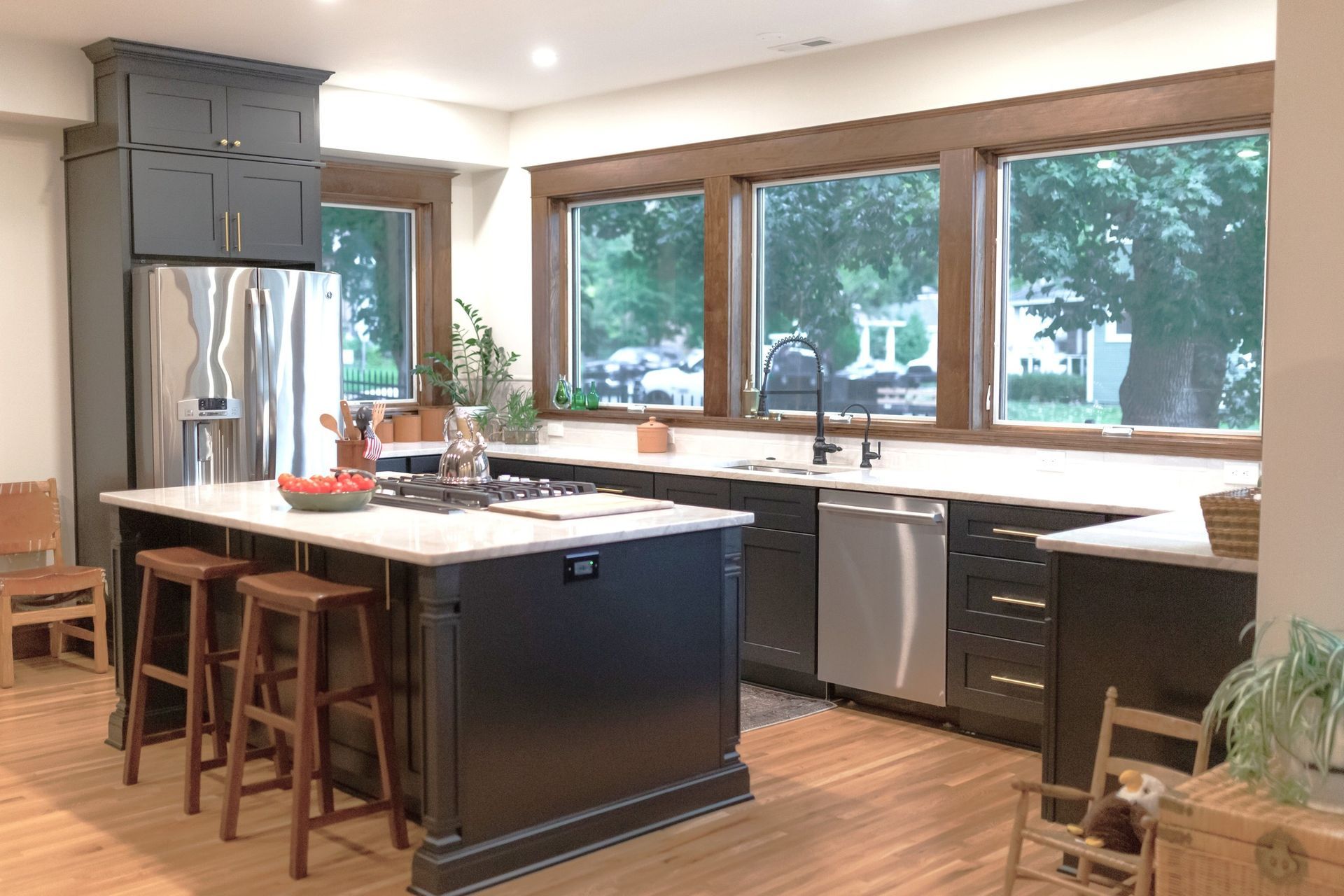 Modern kitchen with dark gray cabinets, a stainless steel fridge, and a large island with wooden stools.