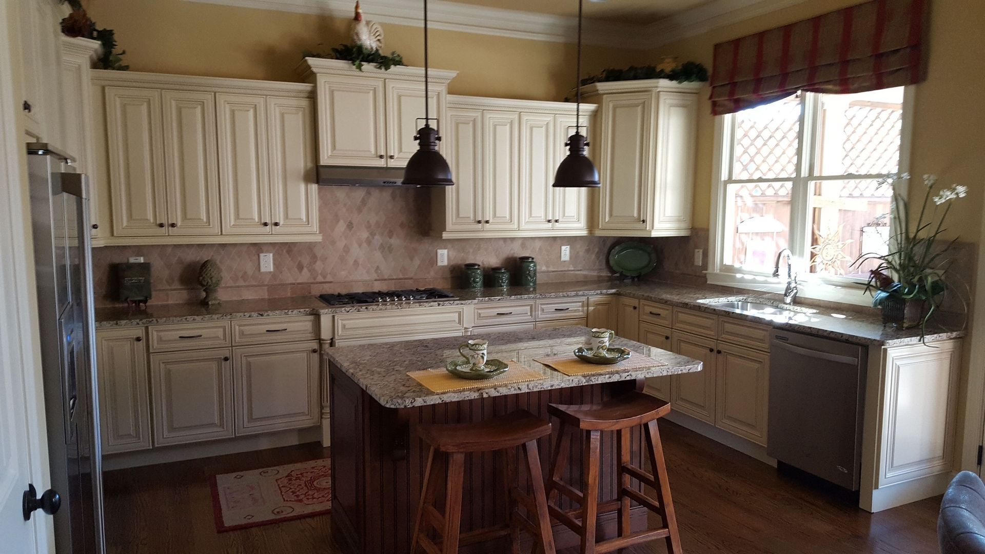 Creamy kitchen with wood island, granite counters, and two brown stools.