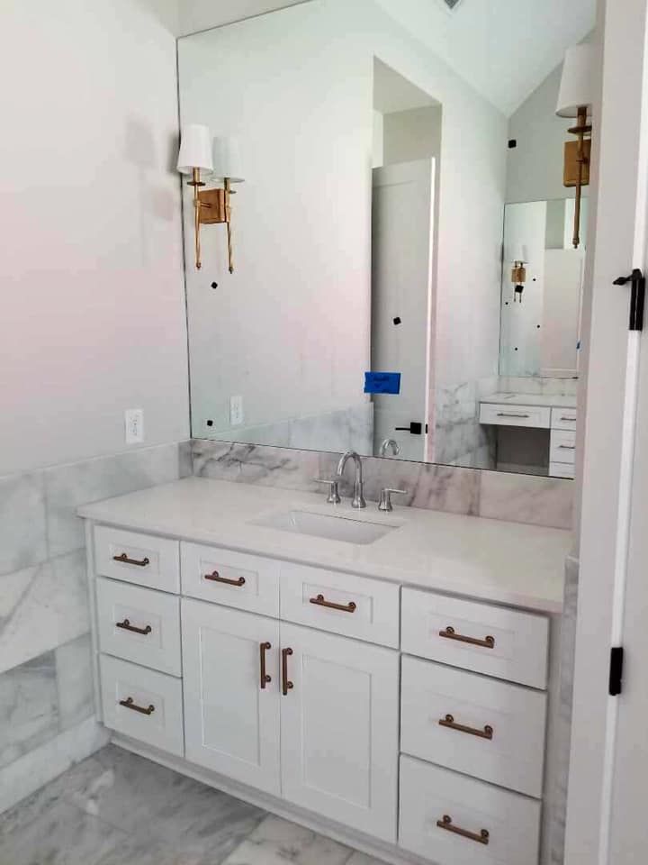 White bathroom vanity with marble countertop and large mirror.