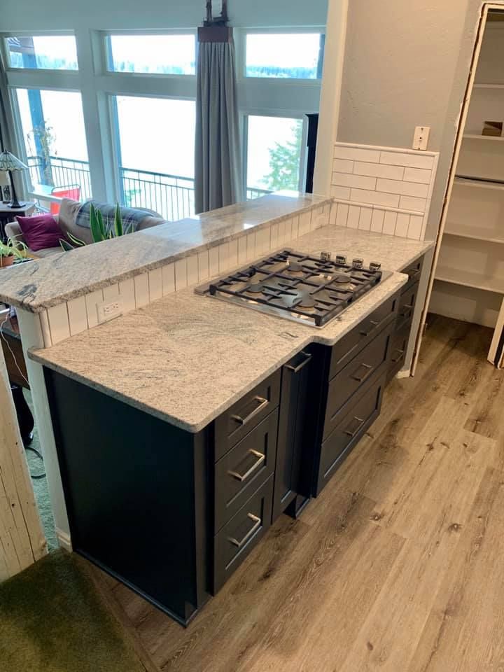 Kitchen island with a gas stovetop, dark gray cabinets, and a granite countertop.