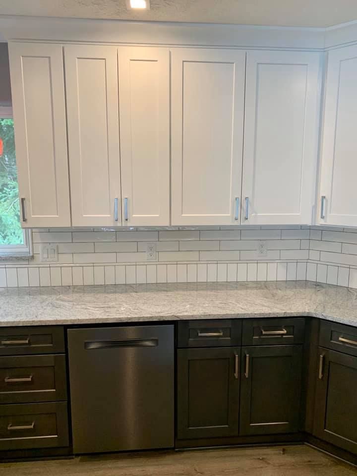 White upper and dark green lower kitchen cabinets with a stainless steel dishwasher.