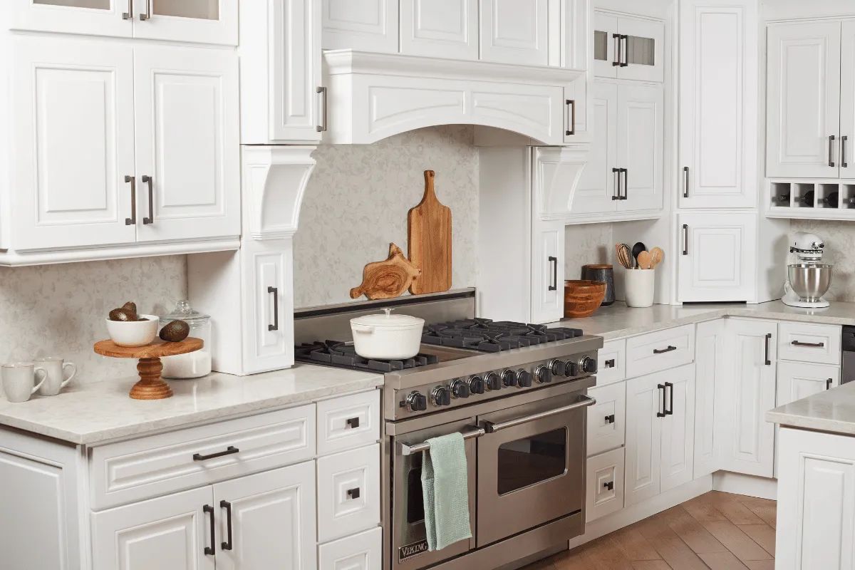 White kitchen with stainless steel stove, cabinets, and light countertops.