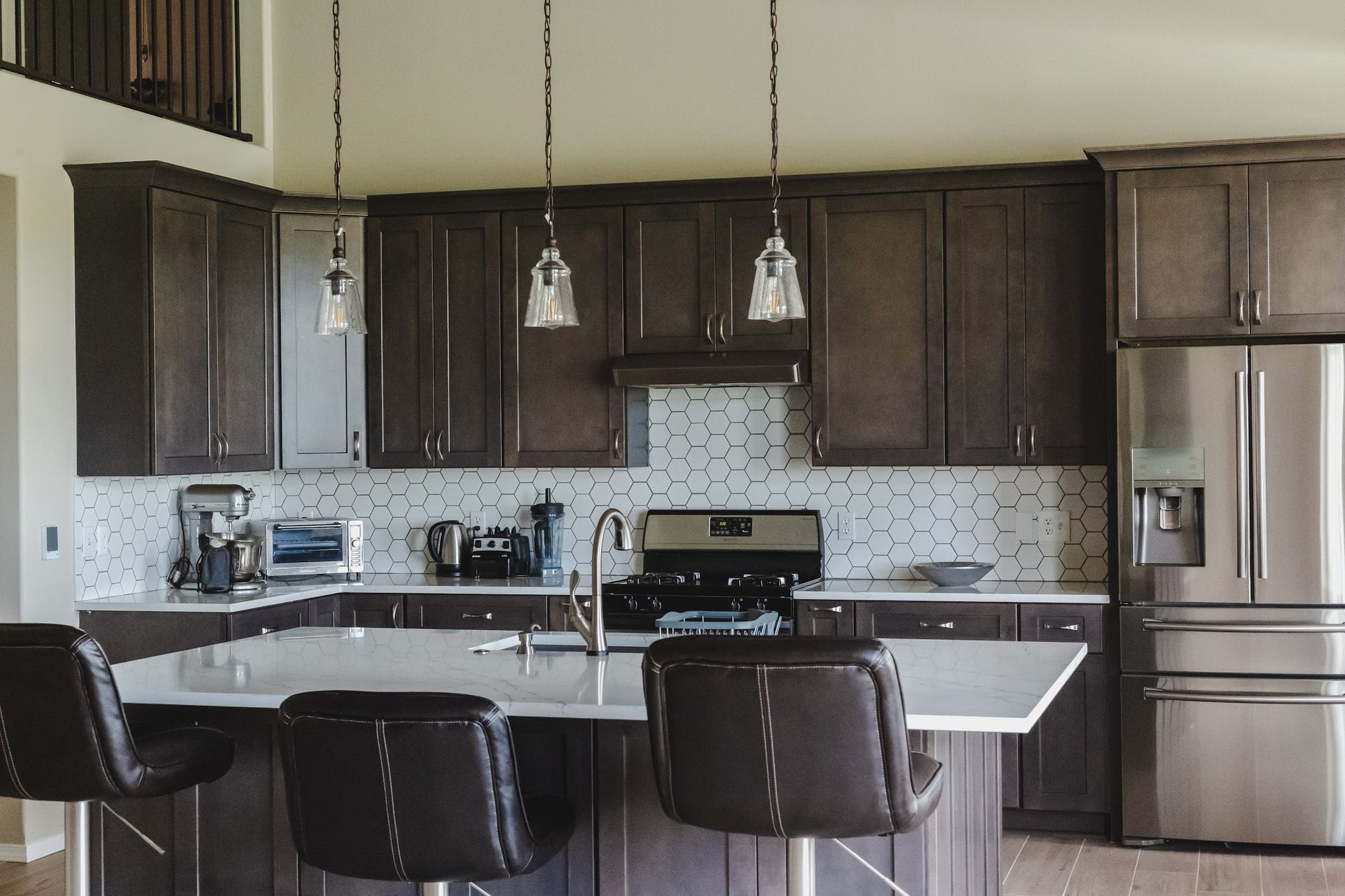 Modern kitchen with dark brown cabinets, white countertops, and stainless steel appliances.