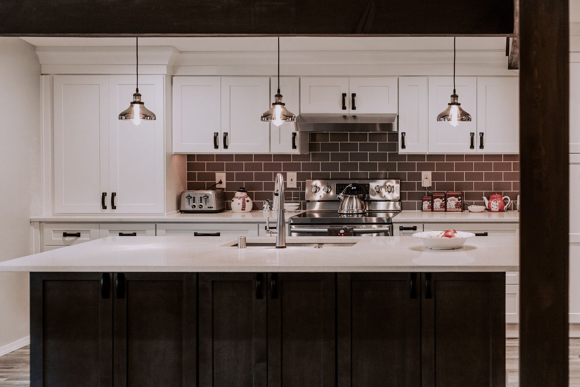 Modern kitchen with white cabinets, dark island, and pendant lights.