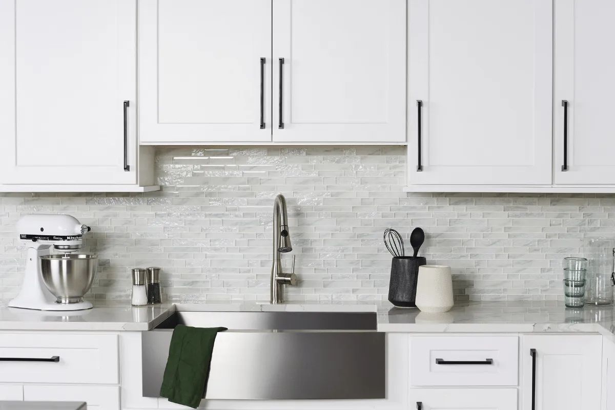 White kitchen with stainless steel sink, cabinets, and appliances.