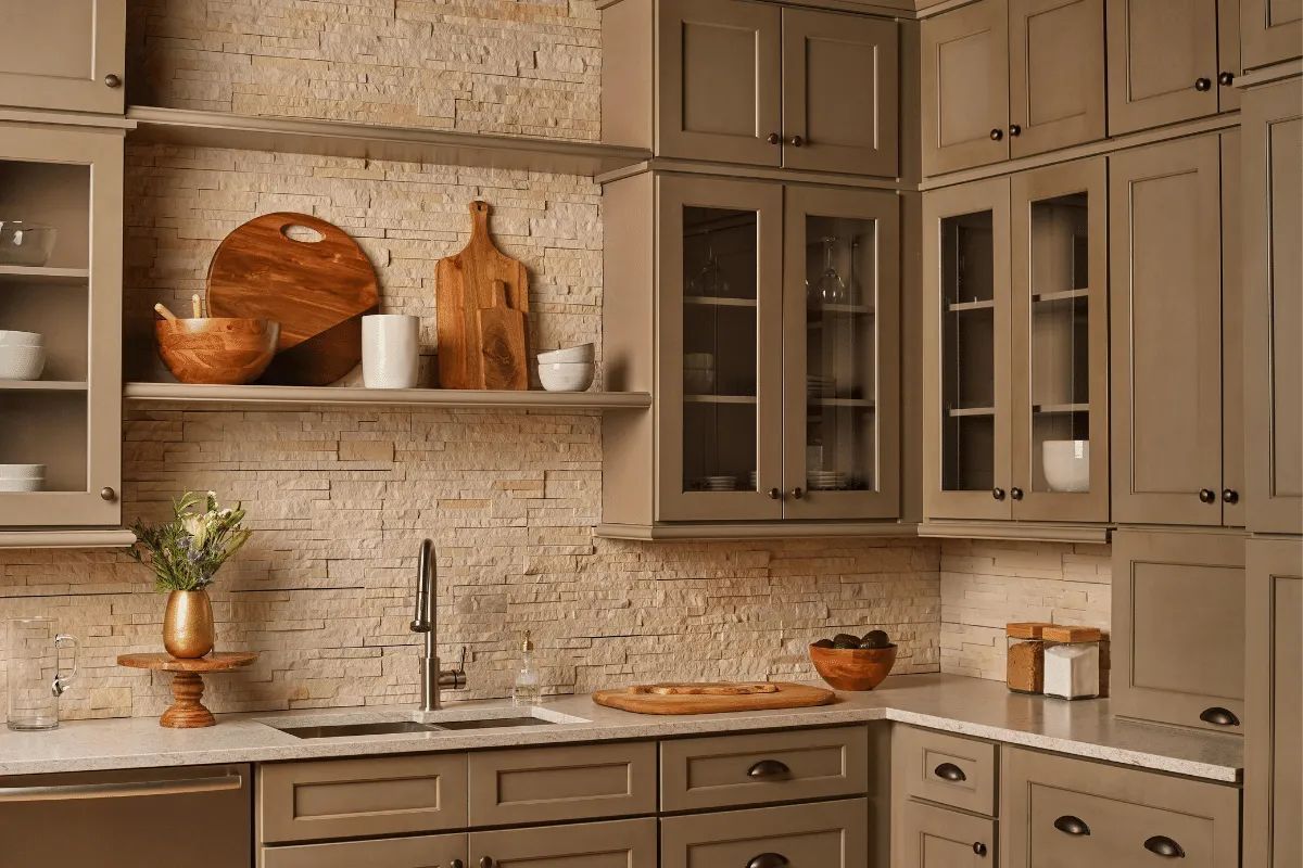 Kitchen with stone backsplash, gray cabinets, open shelves with decor, and a stainless steel sink.