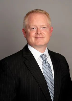 A man in a suit and tie is smiling for the camera.
