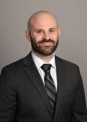 A bald man with a beard is wearing a suit and tie.