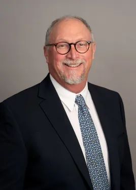 A man in a suit and tie is smiling for the camera.